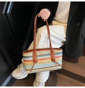 Detail of multi-colored striped woven tote bag with brown knotted shoulder strap