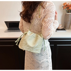 Detail of light green marble texture bucket bag with gold chain strap on a model