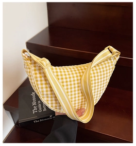 Detail view of yellow checkered crescent bag with adjustable textile shoulder strap