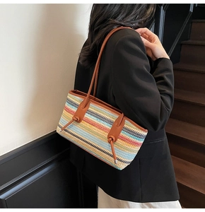 Detail of colorful woven tote bag with brown leather straps worn over a black blazer