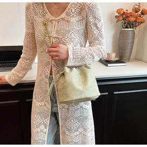 Light green drawstring bucket bag with chain strap shown on a model in a lifestyle scene