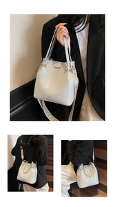 Detail of stone textured bucket bag featuring wide geometric strap and golden hardware