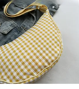 Detail of yellow and white checkered crescent bag with textured seersucker fabric and strap