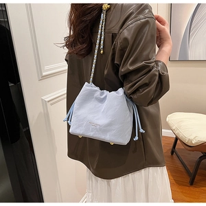 Detail of light blue pleated bucket bag with gold chain strap and brand logo