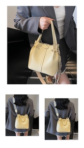 Detail of cream yellow bucket bag with crocodile texture and ethnic style shoulder strap