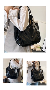 Detail view of glossy oil wax leather tote bag featuring a white chiffon bow decoration