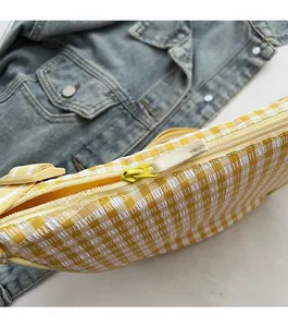 Detail of yellow checkered crossbody bag with textured fabric and smooth zipper