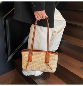Detail of bohemian straw tote bag with brown leather handles and woven texture finish