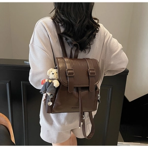 Détail du sac à dos vintage en similicuir marron foncé avec breloque ours sur le mannequin