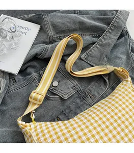 Detail of yellow gingham crescent bag showing seersucker texture and wide strap
