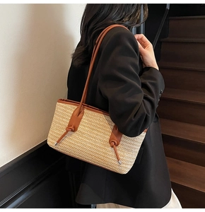 Detailed view of woven straw tote bag with brown leather straps and tie accents