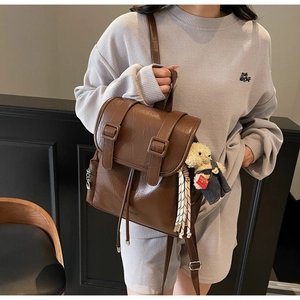 Vue détaillée du sac à dos vintage en cuir marron avec sangles et petit ours en peluche