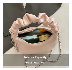 Internal capacity of pink ruched dumpling bag showing phone and makeup inside