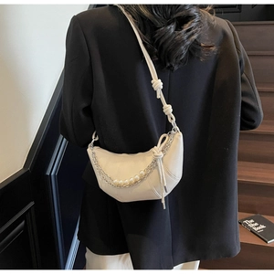 Detail of beige crescent bag with vertical stitching, knot strap and pearl chain decoration
