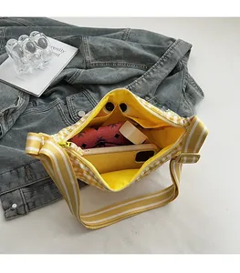 Detail view of yellow checkered canvas bag showing large interior capacity and bright yellow lining