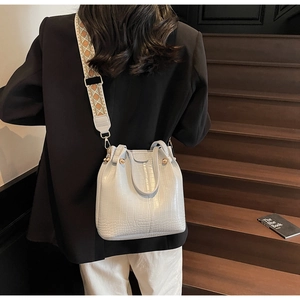 Detailed view of grey croc-embossed bucket bag with embroidered wide shoulder strap