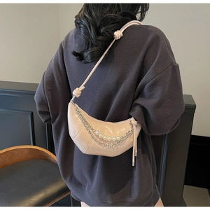 Detail of a light pink patent leather croissant bag with silver chains and pearls