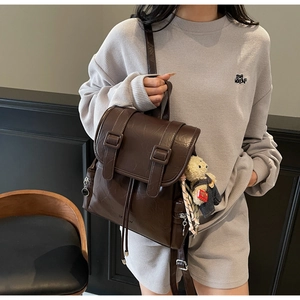 Détail d'un sac à dos vintage en similicuir marron avec boucles en métal et charme d'ours