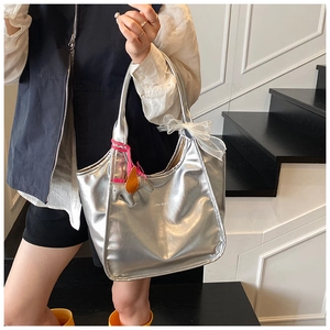 Detail of silver oil-wax leather tote bag featuring colorful charms and brand logo