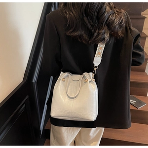 Detail of light grey crocodile embossed bucket bag with ethnic patterned wide strap