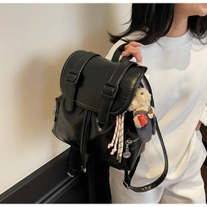 Détail d'un sac à dos noir en cuir PU avec texture vintage et pendentif ours sur un mannequin