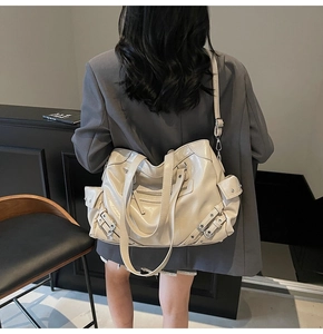 Detail of cream white faux leather tote bag with silver studs and multi-zipper pockets