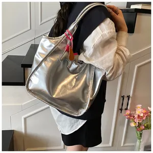 Detail of silver metallic tote bag with horse charm and pink knot on a model shoulder