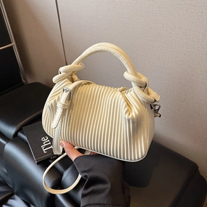 Detailed view of the creamy white pleated handbag with a knotted handle and silver buckles