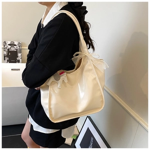 Detail of cream tote bag with lace bow decoration and horse charm worn on shoulder