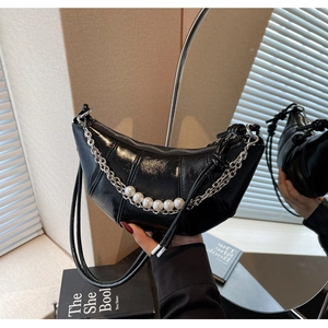 Detail of black crescent handbag featuring a silver chain with five large white pearls