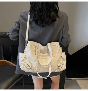Detail view of cream oversized tote bag with metal studs and zipper accents on leather