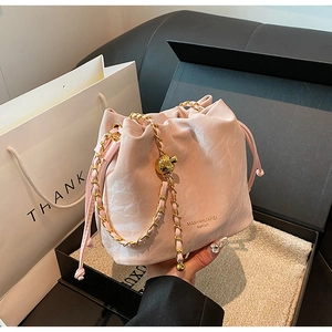 Pink drawstring bucket bag with gold chain strap and marble texture in a gift box setup