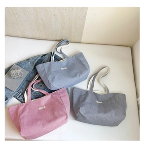 Trois sacs cabas en toile rayée rose, bleu et gris présentés dans un décor de style de vie