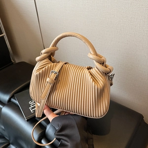 Detailed close-up of beige pleated texture on stylish tote bag with knotted handle