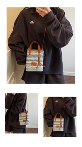 Detail of colorful striped woven mini bag with brown leather handles and side braid charm