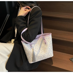 Dettaglio della borsa tote geometrica viola con nappa grigia appesa sulla spalla