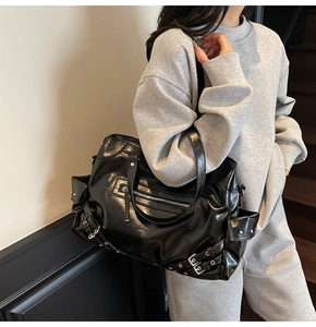 Detail of a large black vintage tote bag with rivets and metal buckles for casual wear