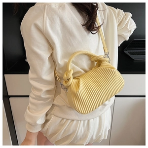 Lifestyle shot of woman wearing a pale yellow pleated crossbody bag with a knotted handle
