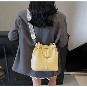 Detail of beige crocodile pattern bucket bag with wide ethnic style jacquard strap
