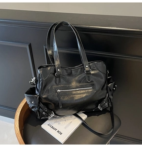 Detail of black glossy tote bag featuring vintage wrinkled texture and multiple zip pockets