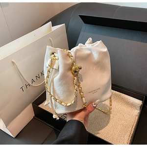 Detail of white drawstring bucket bag with gold chain strap and marble textured leather
