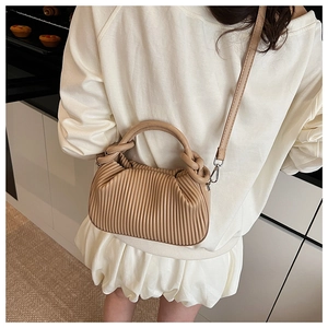Beige pleated handbag with detachable strap shown in a modern lifestyle setting