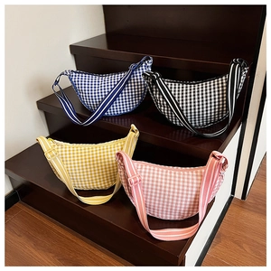 Detail showing colorful plaid crescent bags in blue, black, yellow and pink on stairs