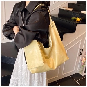 Detailed view of the large pale yellow tote bag with matching zippered pouch on a model