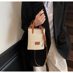 Detail of handwoven striped bucket bag with brown PU leather handle and branding