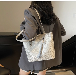 Ricamo dettagliato e ciondolo con nappa grigia su una borsa tote minimalista bianco sporco
