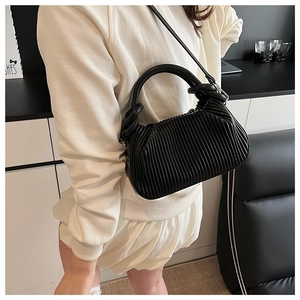 Detail view of the black pleated leather texture and wavy design on a stylish handbag