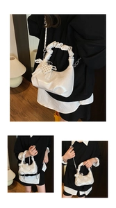 Detail of white pleated hobo bag with pearl bow charm and elegant metal chain strap