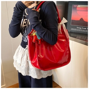Detail of red wax leather tote bag with decorative horse charm and white mesh bow accessory