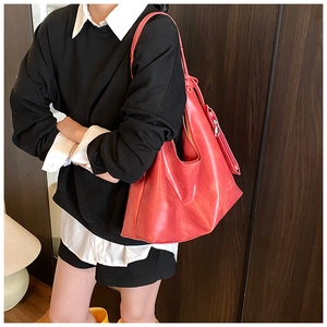 Detailed side view of large red tote bag with metal zipper and matte leather texture